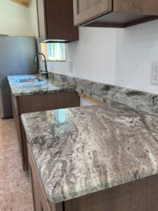 Grey and white granite countertop with bold veining and a matching backsplash in a cabin kitchen