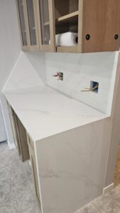 Built-in white quartz counter nook with a waterfall-style side edge and matching backsplash