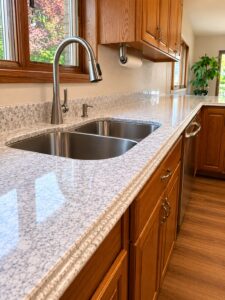Speckled grey and white granite countertop with a stainless steel double-bowl sink and oak cabinets