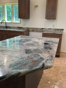 Kitchen island with dramatic warm-toned granite countertop and dark wood cabinetry