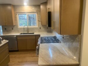 Grey veined stone countertop with a brass faucet, wood cabinets, and integrated LED under-cabinet lighting