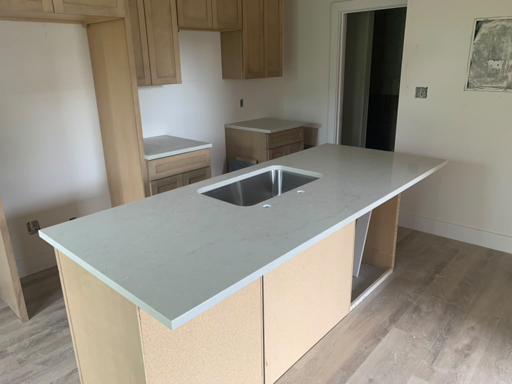 Kitchen island countertop in soft grey veined quartz with a stainless steel sink cutout