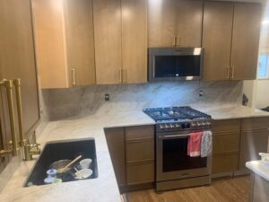 Kitchen countertop and backsplash with soft veining, brass hardware, and a stainless steel range