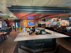 Restaurant back bar area with a speckled quartz countertop, beer taps, and overhead televisions