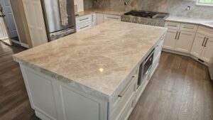 Large kitchen island countertop with dramatic honey-toned veining and white cabinetry