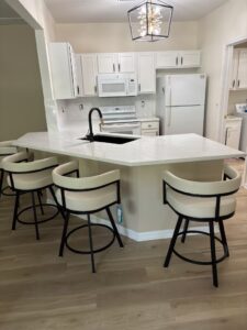 White kitchen island with soft veined quartz countertop and cream bar stool seating